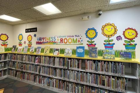 Children's Room - picture books section and sign "Happiness blooms inside this room" with flowers on wall